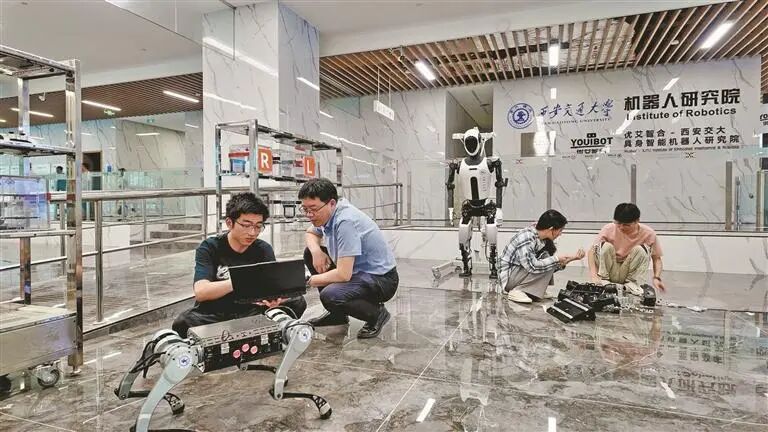 西安交通大学具身智能机器人研究院副院长徐俊（左二）在实验室指导学生调试机器人设备（资料照片）。